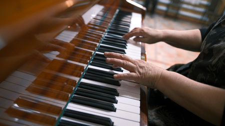 A woman plays the piano, focusing on the hand and the keys. Elderly pianist's hands, close-up. Piano lessons at a music school. The musician composes a new melody. Concertの写真素材