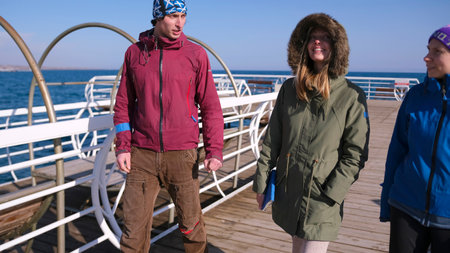 Three people are walking along the pier. The scene is relaxed and friendly.