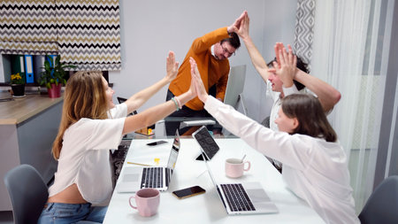 A group of people high-fives each other in a conference room. The concept of success. Home business...