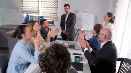 The office staff congratulates their colleague on a successful report. A group of people claps their...
