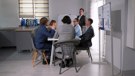 A group of lawyers is sitting at a table in a conference room and discussing the defense of a new...