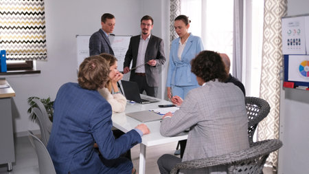 Two men and a business partner are holding a presentation at the company's office. A group of people...