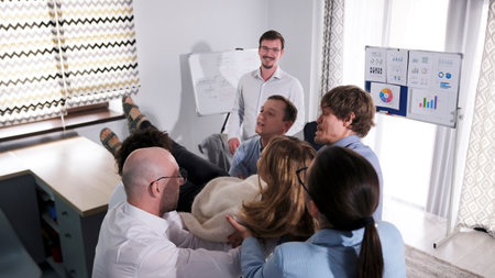 The happy mentor is happy for his team, which has learned mutual support and trust. A group of people caught their female colleague in mid-air. The scene is carefree and playfulの写真素材