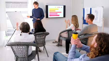 The audience applauds the young lecturer. A professional mentor conducts business training. A group...