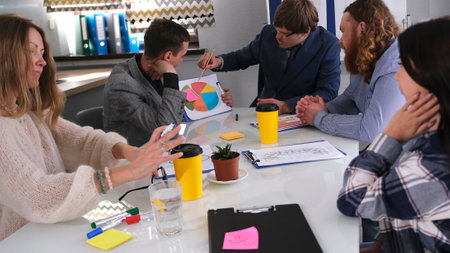 The head of the department holds a briefing in the meeting room. A group of people is sitting at a table and discussing a business development strategy in a crisis.の写真素材