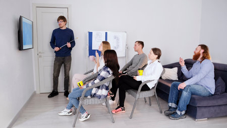 A successful company manager makes a presentation in front of his colleagues. A group of people is...