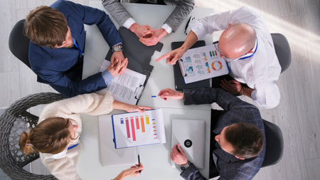 Company managers discuss the profitability of a business project, top view. A group of people is...