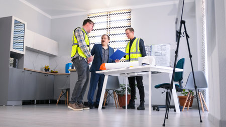 The contractor talks with the builder and the engineer of the architectural bureau. Three people are...