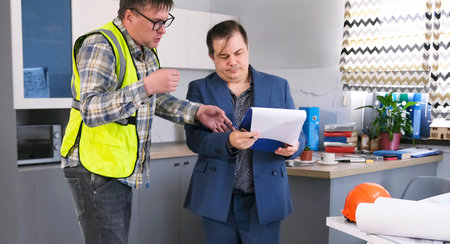 The foreman clarifies the details of the construction project. Two men are standing in an...
