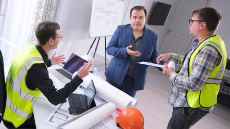 The chief engineer and his assistant ask the boss for a raise. Three men are talking in the...