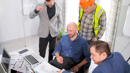 The construction contractor discusses the project estimate with the company's management. A group of...