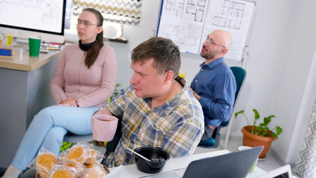 Two men and a woman are drinking coffee in the conference room of a family office. Three people are...