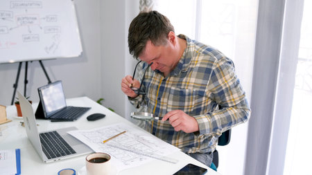 A middle-aged man examines a piece of paper with a drawing using a magnifying glass. The chief...