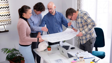 A team of serious professional engineers studies the drawings and plans. A group of people gathered...