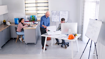 A group of office people work in an architectural bureau. The engineer coordinates the design of the...