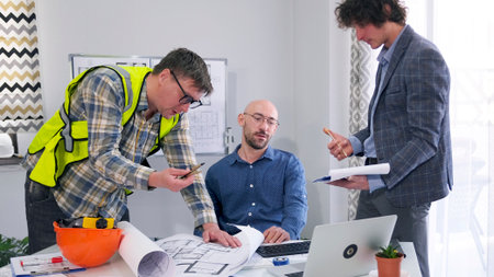 A professional team of architects, builders and engineers is working on drawings and plans for a...