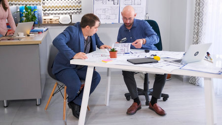 Two successful men coordinate the project budget. The engineer reports to his boss about the work...