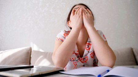 Stress, pain, depression. A worried woman is crying with her face in her hands. A woman is sitting at a table with a tablet, a phone and a notebook.の写真素材