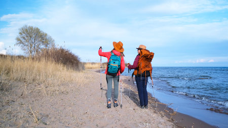 Two female hikers are looking at the sky. Girlfriends strolling along the beach at sunset. Vacation...