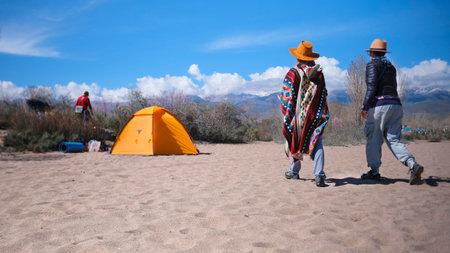 Two women are walking along the beach with a tent in the background. The scene is peaceful and relaxing. A group of friends is relaxing on the beach. Tourism and vacationsの写真素材