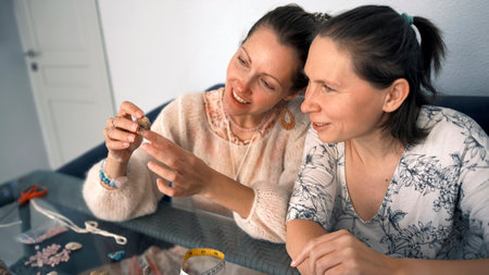 Women's hobby. Two lesbians are engaged in creativity. The women are sitting at a table, one of them...