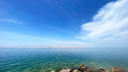 Beautiful blue ocean with a few clouds in the sky. The sky is clear and the water is calm. Rocky seashore. A serene blue lake. The beauty of nature. Vacationの写真素材