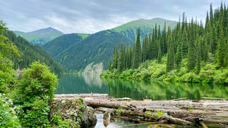 Unique natural monument of Kazakhstan is the Middle Lake Kolsai. Beautiful mountain range with a lake in the foreground. Green hills, mountains and rocks. Concept of calm and serenityの写真素材