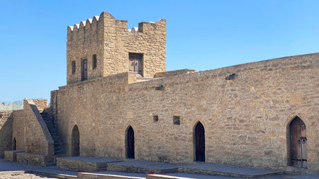 A large old stone building with a tower and arched doorways. Ateshgah is a temple of fire in...