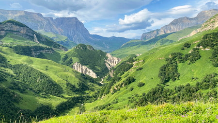 Aerial view of a picturesque green valley surrounded by high mountains, cliffs and ridges. Beautiful...