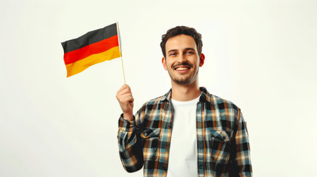 A man holds a German flag in his hands and smiles. The flag is black, red and yellow. The concept of celebrating German Independence Day. Immigration. Travel and tourism. A sports fan.の素材