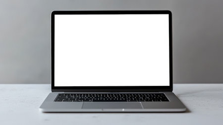 A modern, stylish laptop with a white blank screen sits on the table. The concept of the website presentation. Laconic laptop mockup, straight view. Productivity and focusの素材