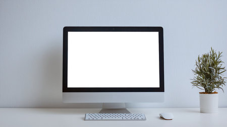 A computer monitor, keyboard and mouse are on the table next to a potted plant. Mockup of the computer display for website advertising. The concept of tranquility and simplicity. Blank screenの素材