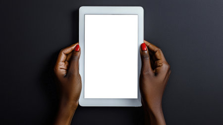 Close-up of a black woman with a red manicure holding a white tablet with an empty screen on a black background. Stylish tablet mockup. Presentation of the website or applicationの素材
