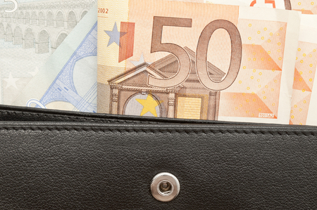 leather black leather wallet with money, some banknotes in black purse, open purse with paper money with moneyの写真素材