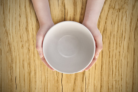 Hunger concept. Female holding empty plate waiting food. Empty plate in handの写真素材