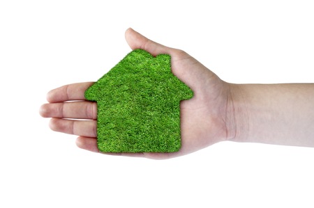 Green grass home icon in his hand. Abstract green grass house on over white background. Ecology concept.の写真素材