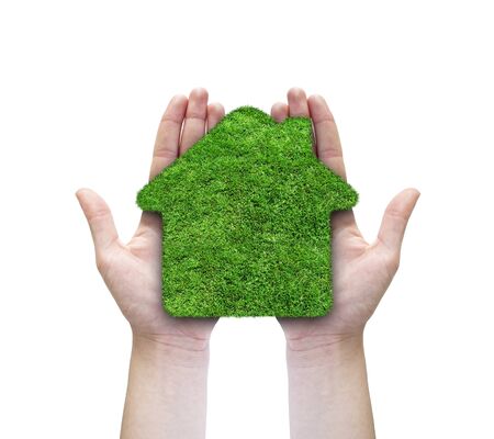 Green grass home icon in his hands. Abstract green grass house on over white background. Ecology concept.の写真素材