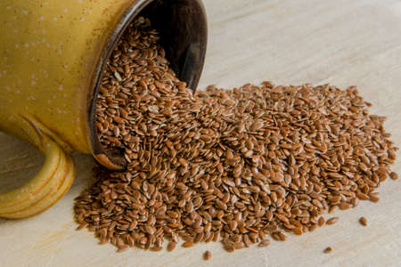 Flax seeds in a cup on wooden backgroundの写真素材