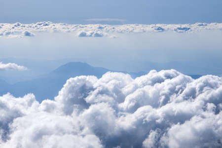 Fluffy clouds over the mountains view from the airplane windowの写真素材