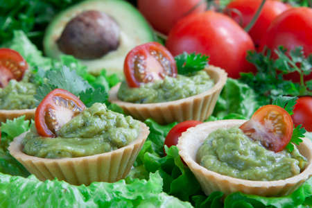 Canapes with guacomole on a vegetable backgroundの写真素材