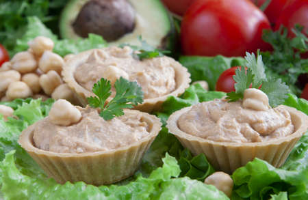 Canapes with hummus on a vegetable backgroundの写真素材