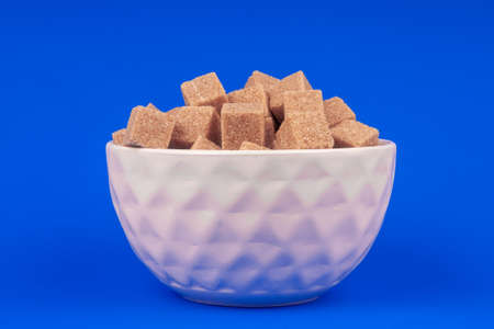 Bowl of cane sugar on a blue background top viewの写真素材