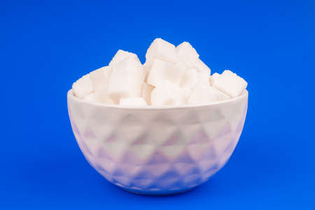 Bowl of white sugar on a blue backgroundの写真素材