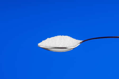 Spoon with white sugar on a blue backgroundの写真素材
