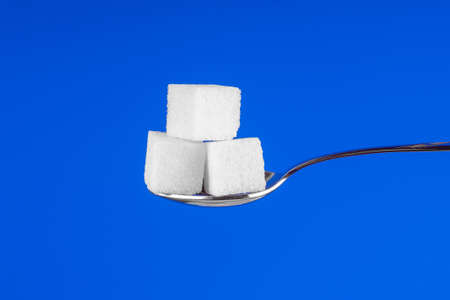 Spoon with white sugar cubes on a blue backgroundの写真素材