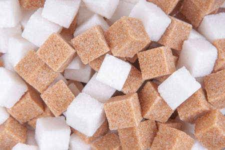 Cane sugar and white sugar cubes background top view textureの写真素材