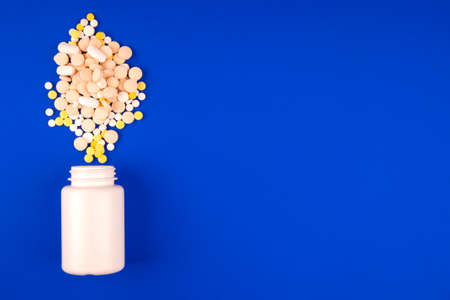 Pack with a heap of medical multicolored pills on a blue backgroundの写真素材