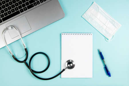 Flatlay doctor workplace with laptop, mask and with notepad mock up.の写真素材