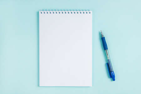 Flatlay notebook and pen on a table on a blue background. Mock up