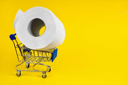 There is no toilet paper. Shopping cart for products with toilet paper on a yellow background. Concept of lack of grocery store pandemic Covid-19.の写真素材